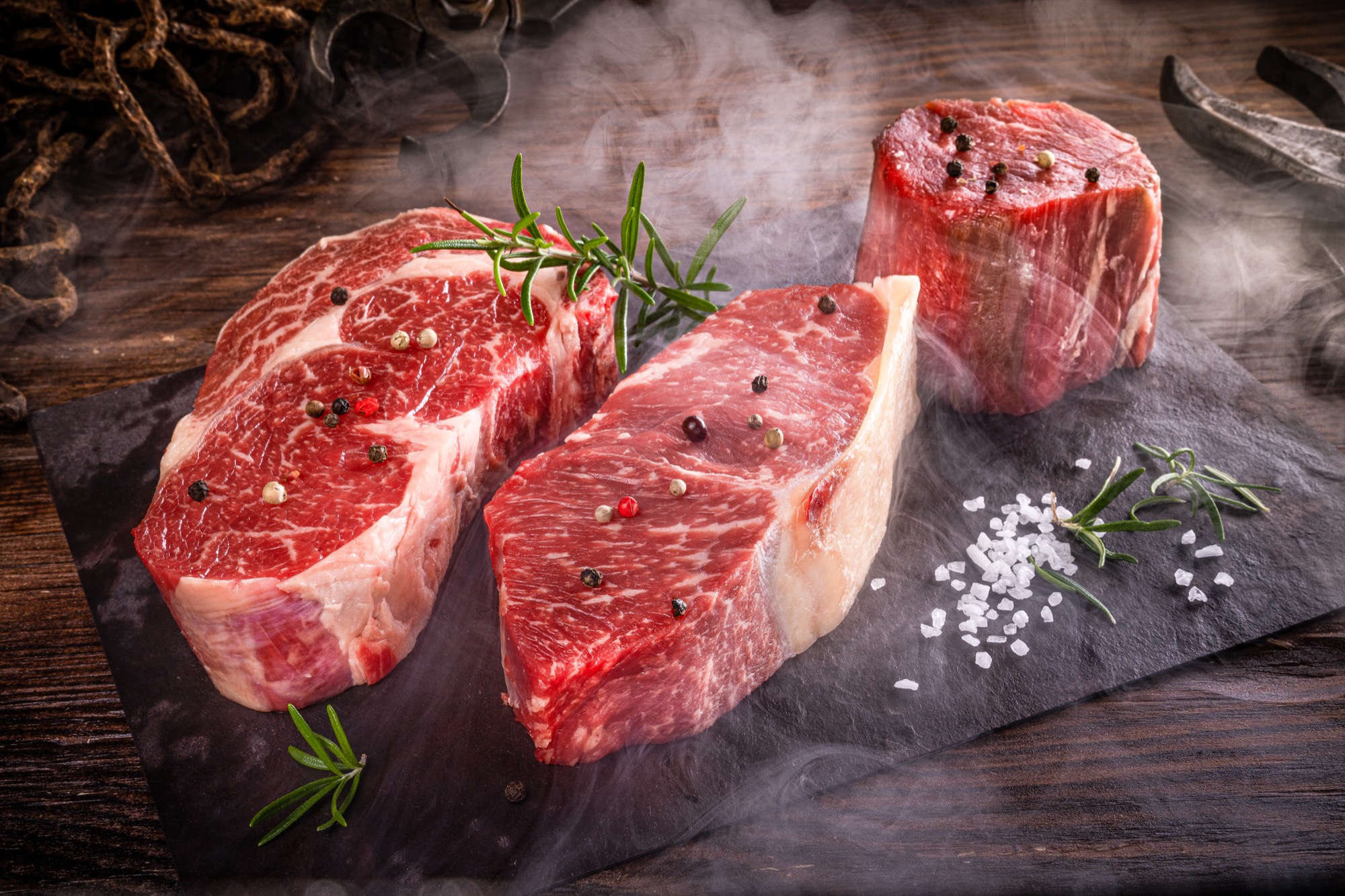 Rohe Steaks mit Rosmarin und Pfeffer auf einer Schieferplatte